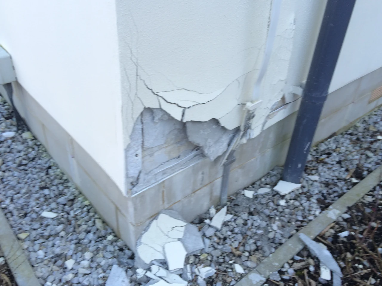 Cracked and detached render at a lower external wall corner in Buxton