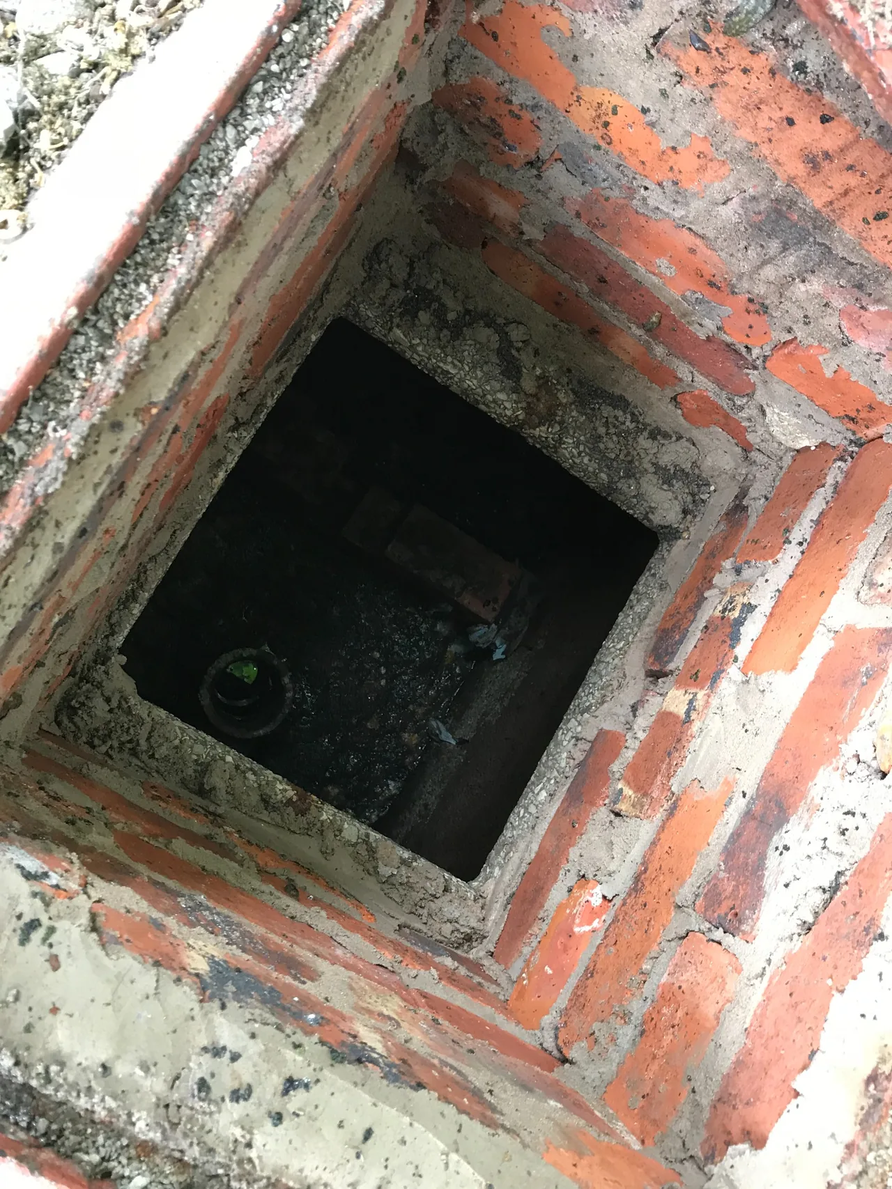 Closer view inside the open masonry chamber serving the private foul drainage system in Buxworth