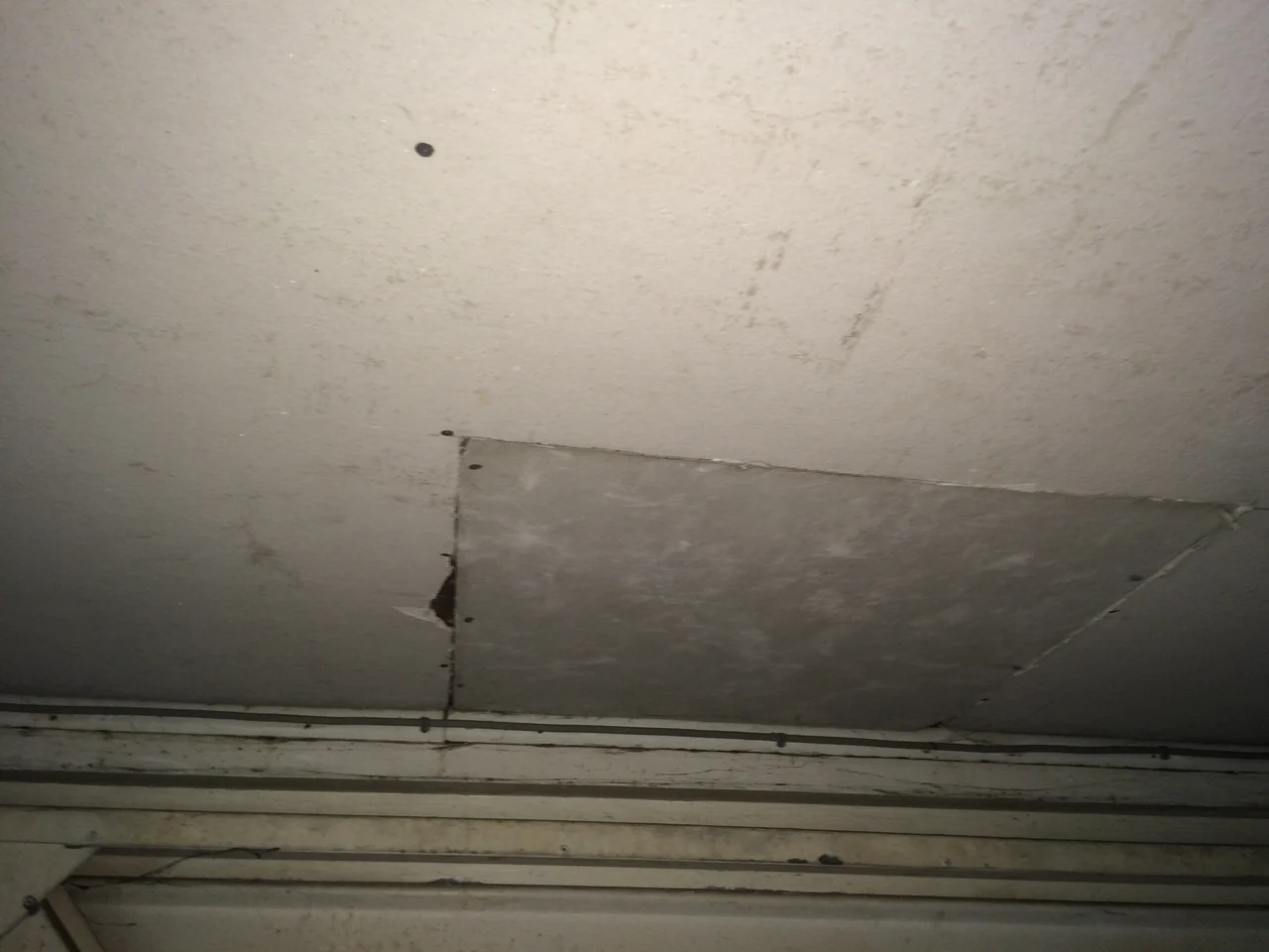 Stained garage ceiling boarding with a damaged edge and patch panel in Disley