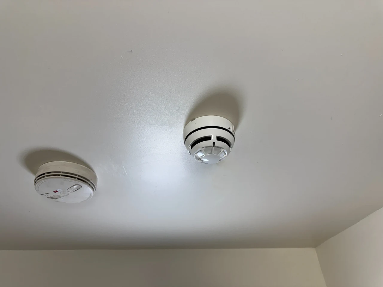Communal-system detector beside a separate domestic smoke alarm in Heaton Moor