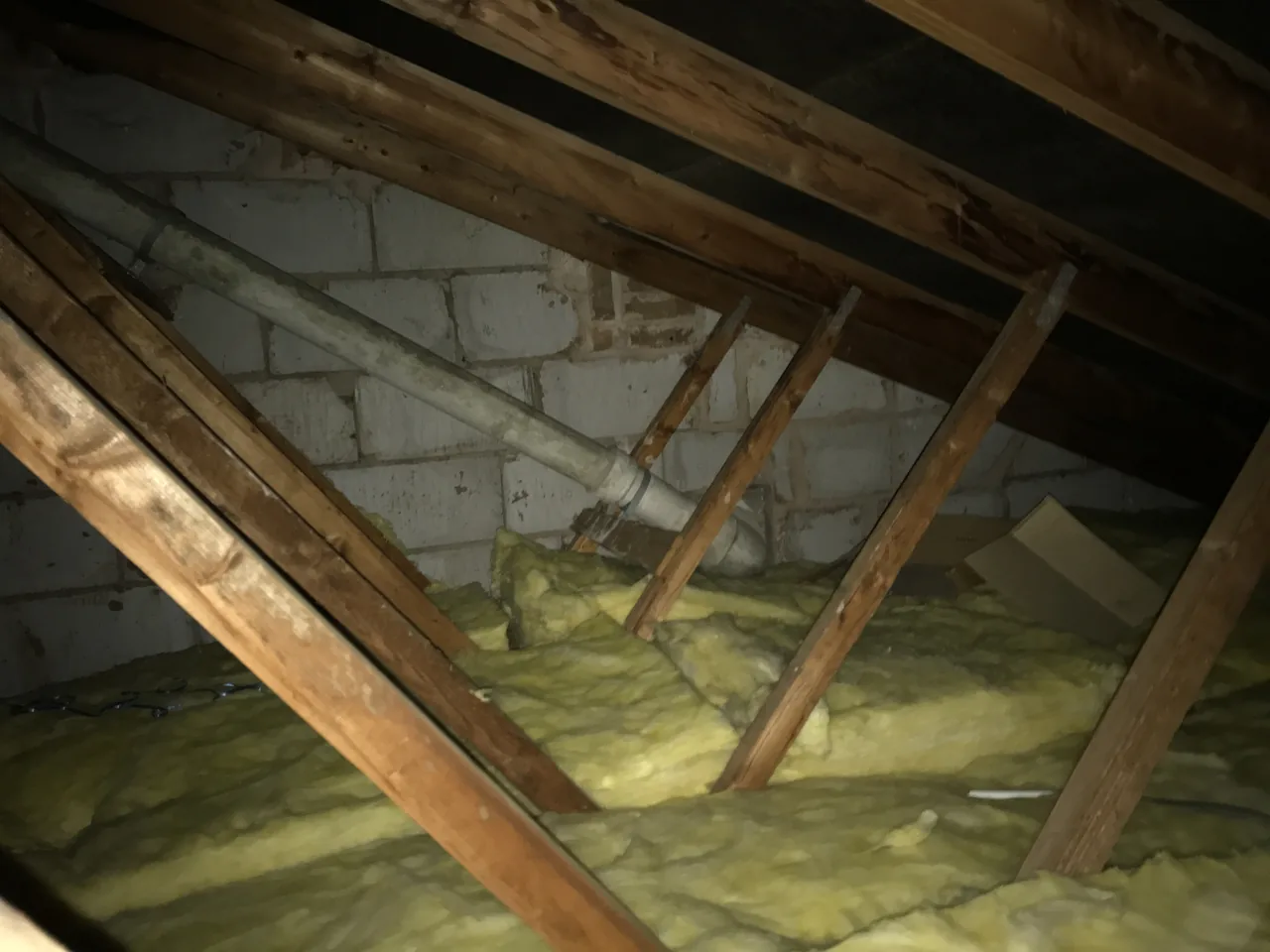 Prefabricated timber roof trusses beside a masonry wall above deep loft insulation in Offerton