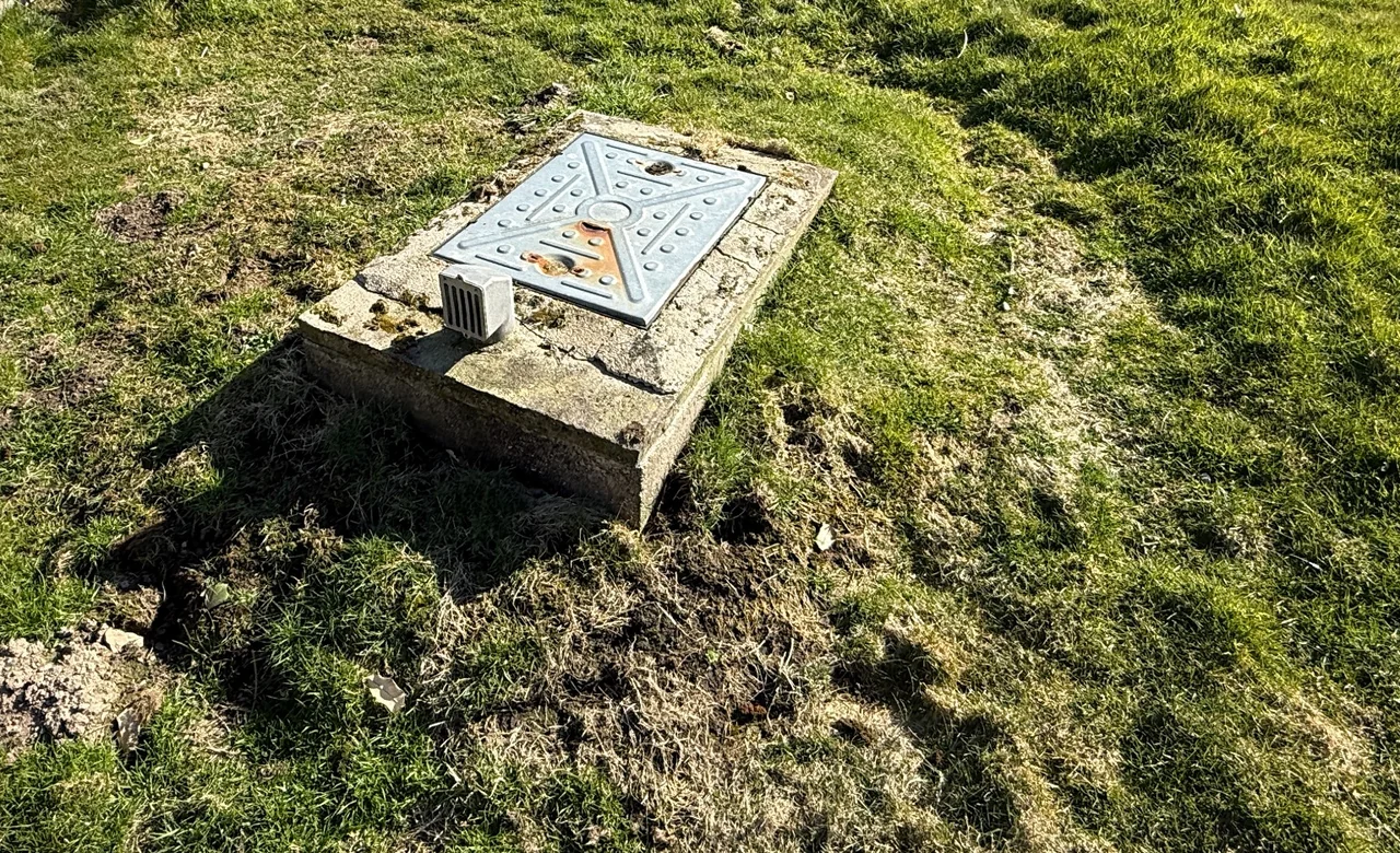 Private drainage access cover on a raised concrete surround with an adjacent vent in Rhoscolyn, Anglesey