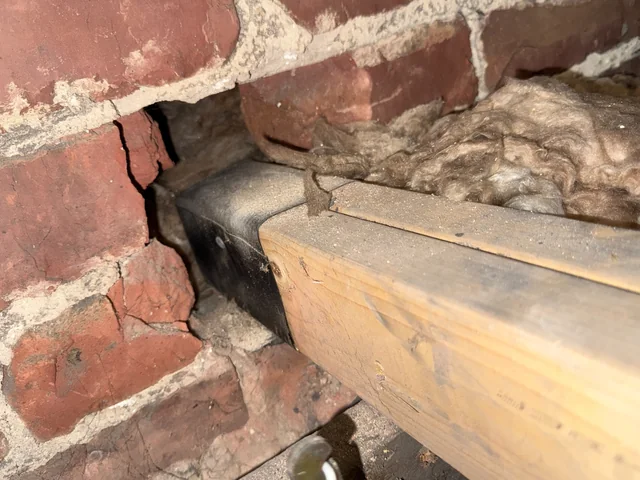 Cracked brickwork beside the bearing of a timber in a roof space