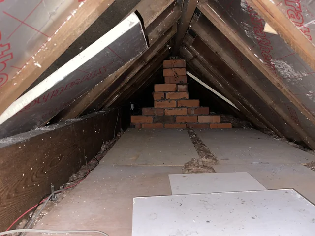 Roof timbers, foil-faced insulation and stepped brickwork within a roof space