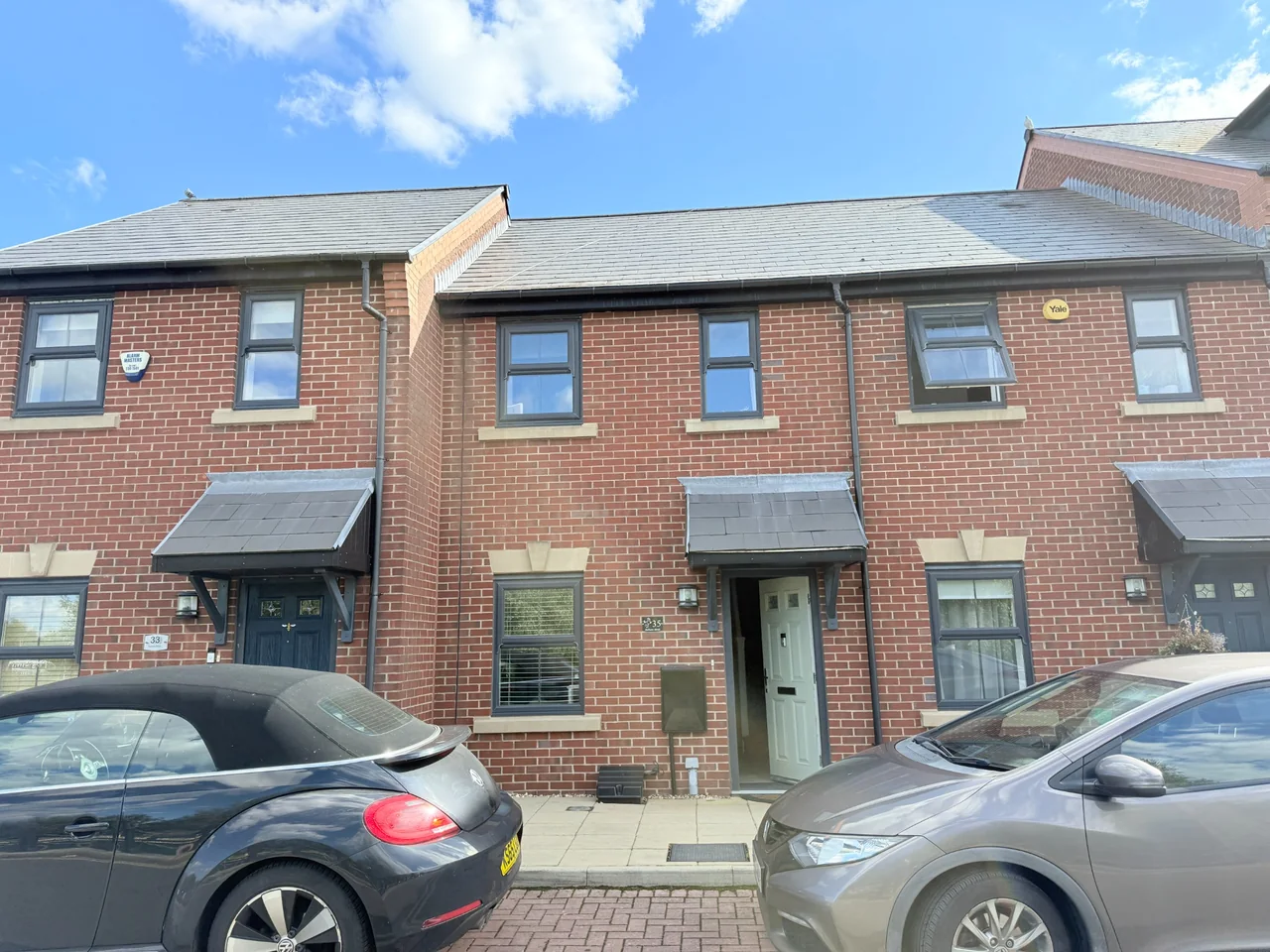 Modern red brick terraced housing with slate roofs and grey framed windows