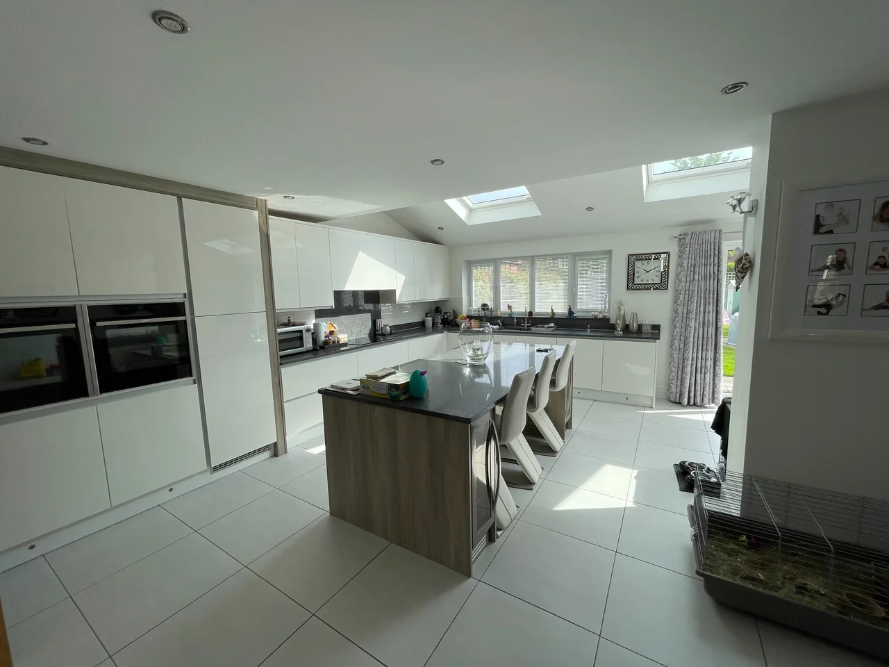 Kitchen extension with white cabinets, an island and rooflights over the dining area