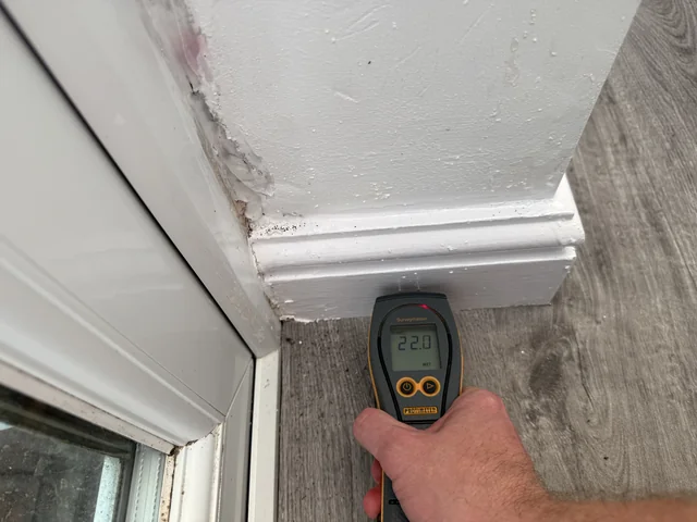 Hand-held moisture meter used against the base of an internal wall