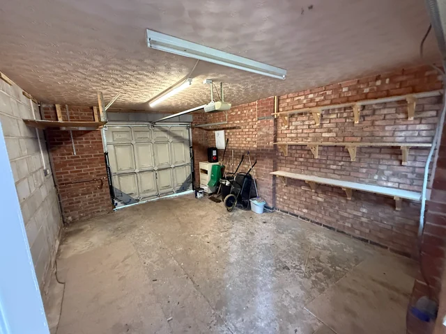 Garage interior showing its door, brick walls, ceiling and concrete floor