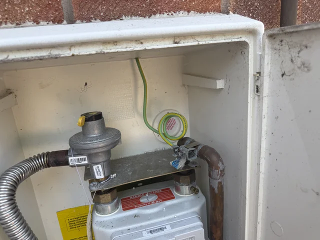 Gas meter, regulator and visible pipework within an external cabinet