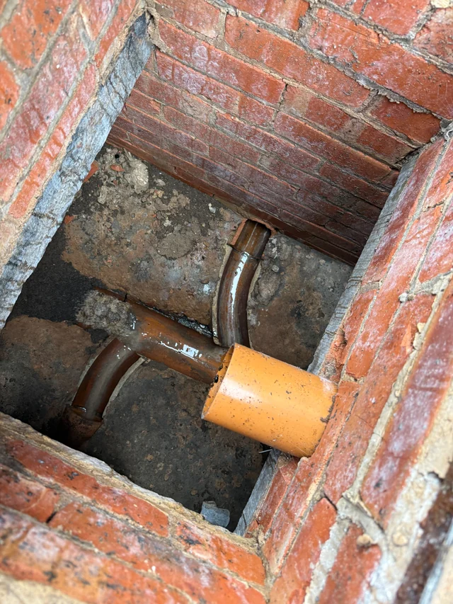 Open brick drainage chamber with visible pipe junctions and channels