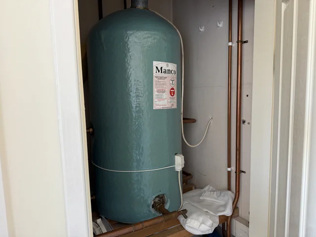 Insulated hot water cylinder and accessible pipework in a cupboard