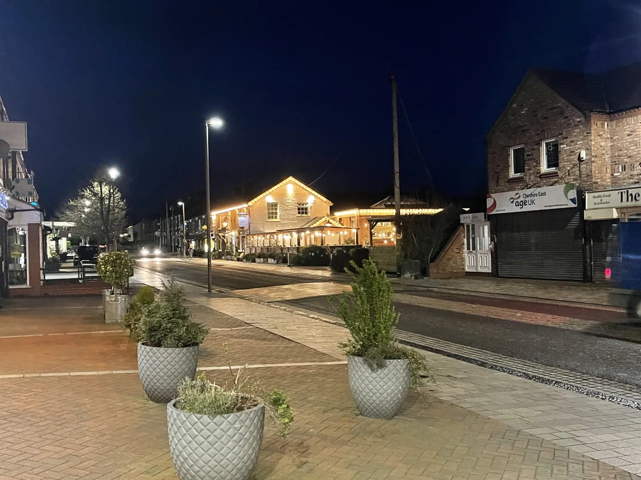 Poynton town centre with illuminated buildings and shops in the evening
