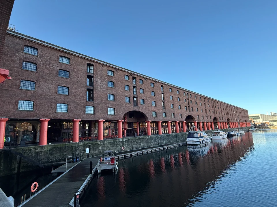 Long brick waterfront building beside a dock with moored boats