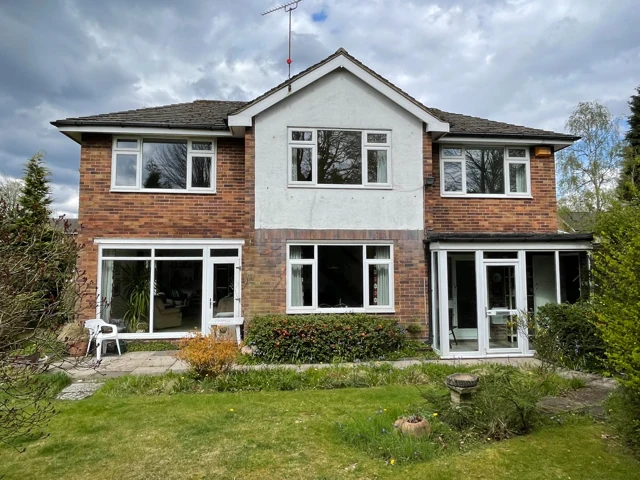 Detached house with broad windows, a rendered central section and a rear garden