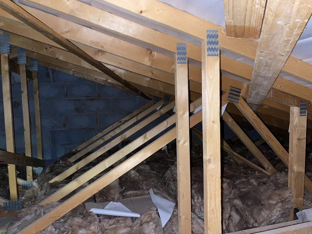 Timber roof trusses, metal connector plates and insulation in a roof space